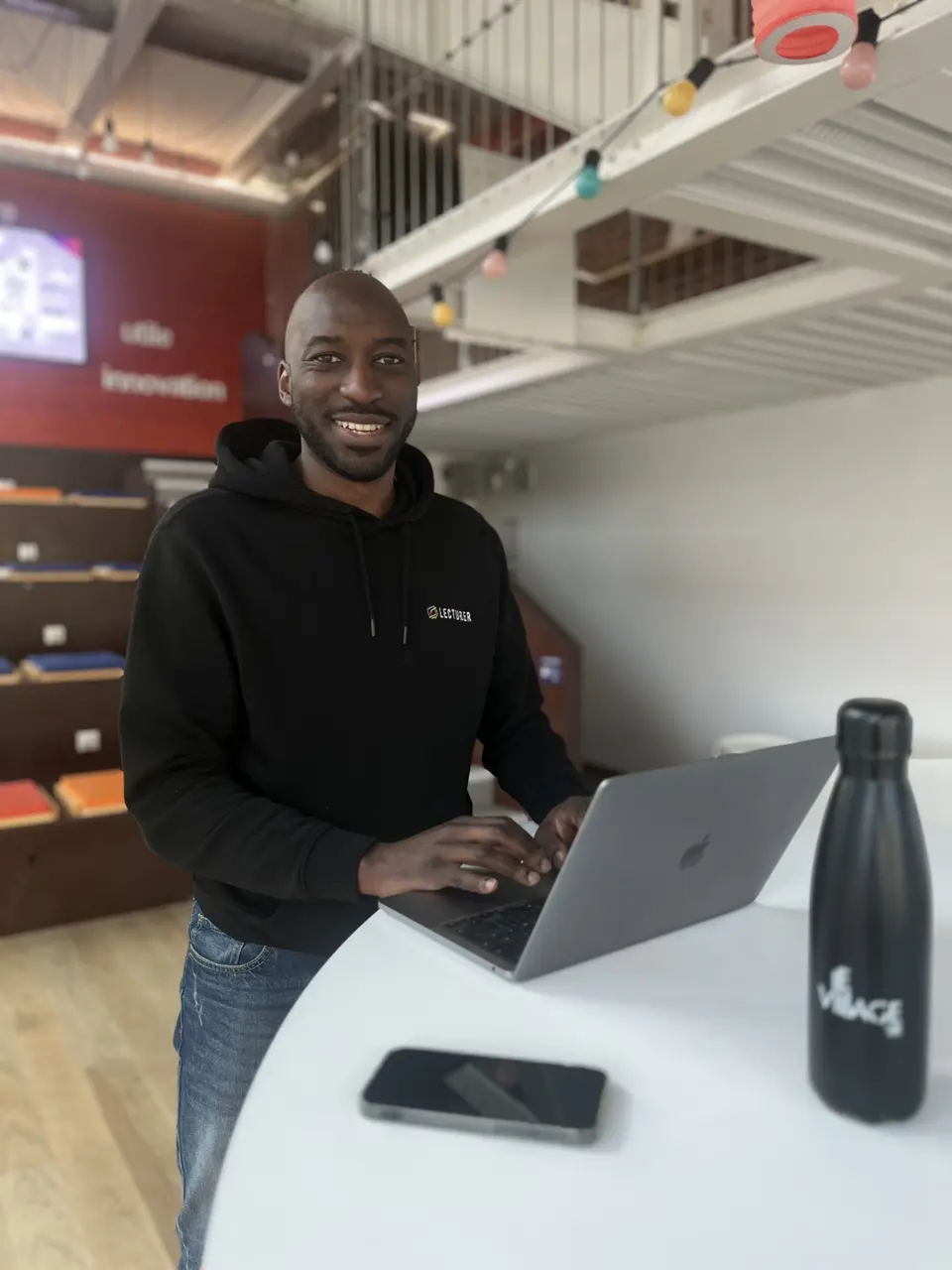 Stevie Bengono, en sweat à l’effigie de Lecturer, au travail sur son ordinateur portable