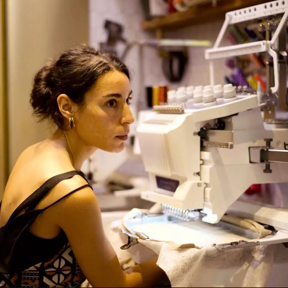 Brodeuse de l'atelier Les Brodeuses, Paris 15e, devant sa machine à broder